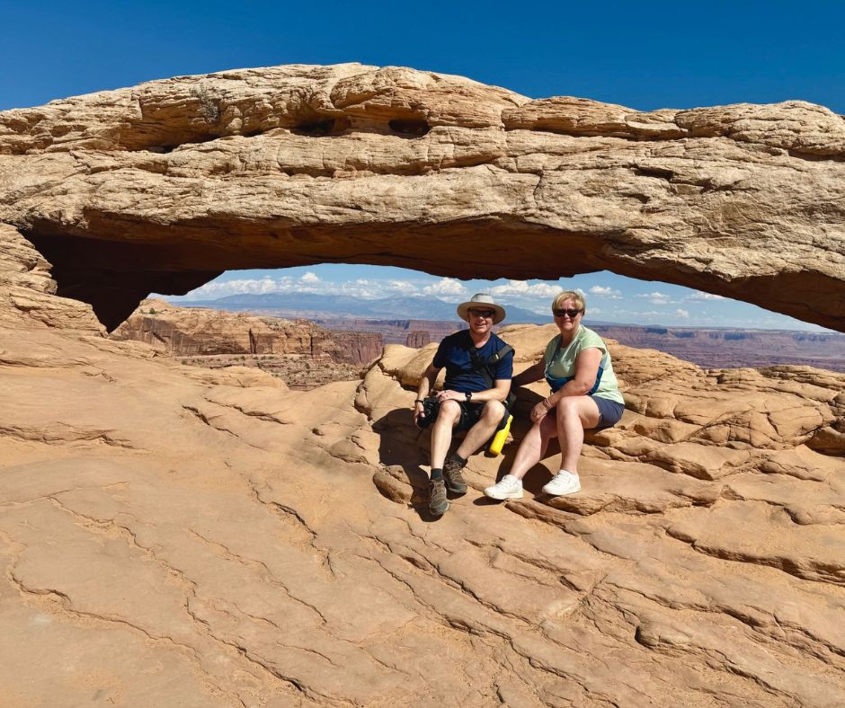 Paul and Hazel sitting beneath a rock arch in the American canyonlands."