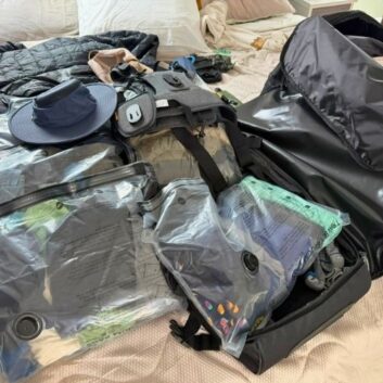 Camera gear and folded clothing laid out during final packing for a three-week trip